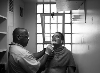 A Gold Coat helps an inmate with dementia shave. 